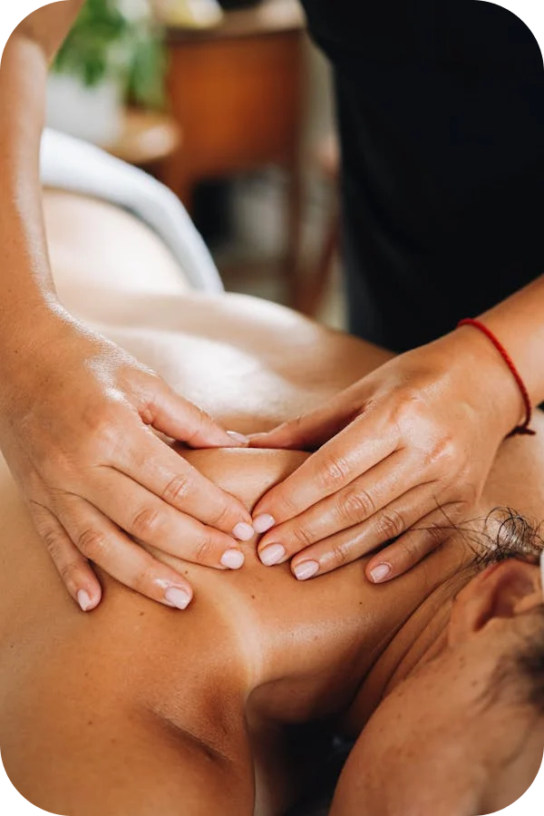 A detailed shot of a physiotherapist's hands providing a therapeutic massage on a patient's upper back and shoulder area to relieve muscle tension.
